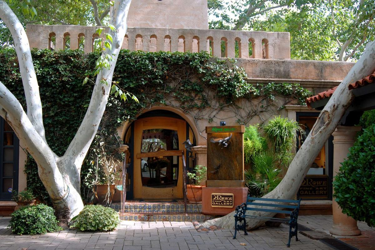 Ivy-covered entrance of Rowe Fine Art Gallery with bronze eagle fountain, beneath the Tlaquepaque bell tower in Sedona
